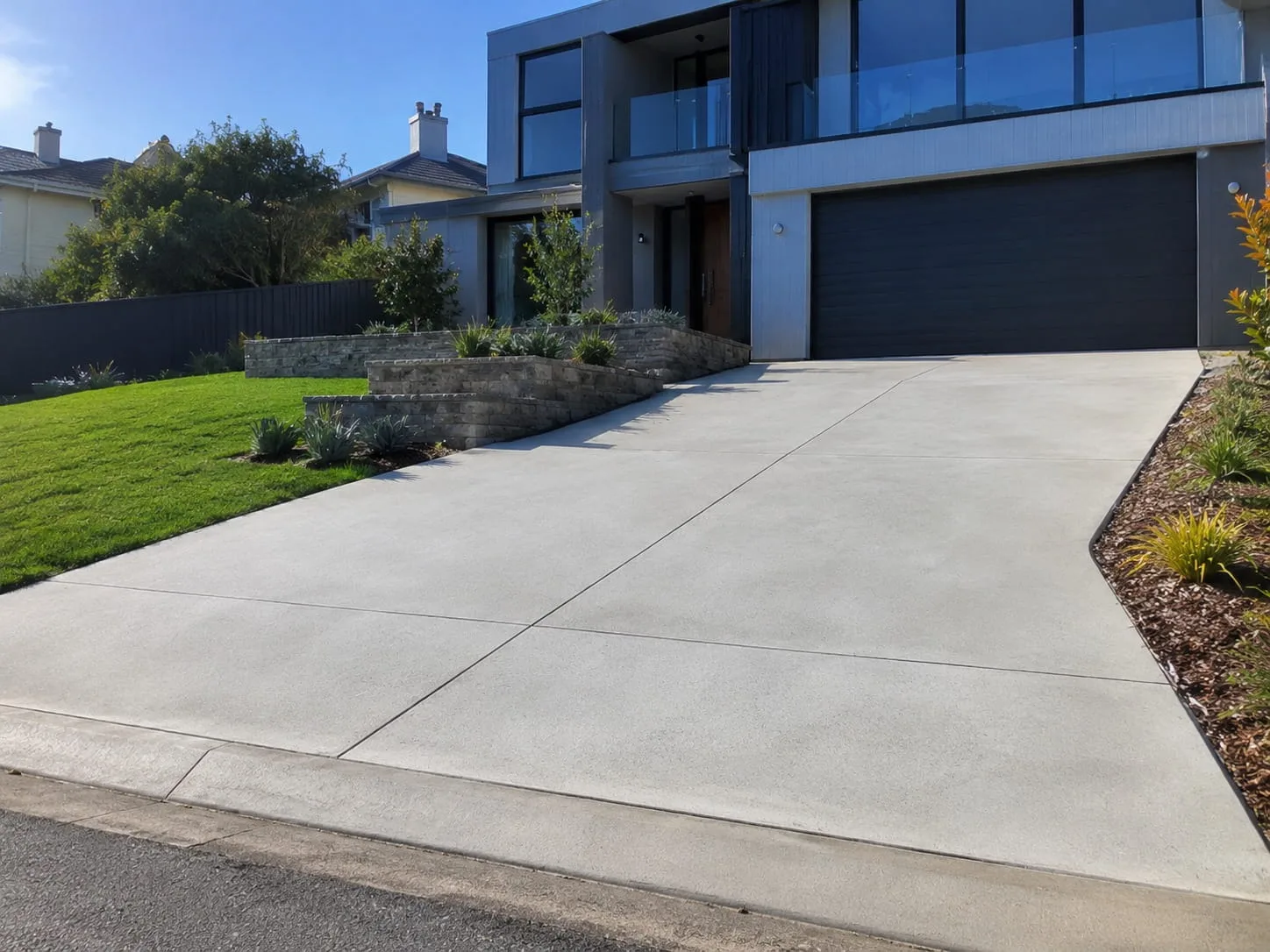 Wide plain concrete driveway sweeping up to the double garage of a modern two-storey Newcastle home