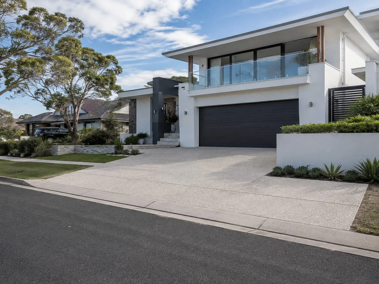 Widened concrete driveway meeting the kerb in front of a double garage at a modern Newcastle home